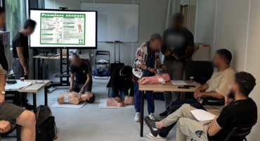 Formation pratique aux gestes de premiers secours avec utilisation de mannequins pour adultes et nourrissons dans une salle de formation.