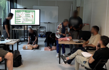Formation pratique aux gestes de premiers secours avec utilisation de mannequins pour adultes et nourrissons dans une salle de formation.